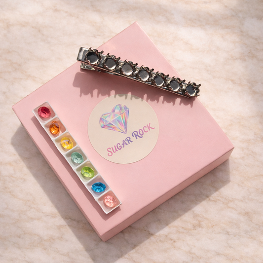 Pink jewelry box with colorful stones and a decorative hair clip on a light background